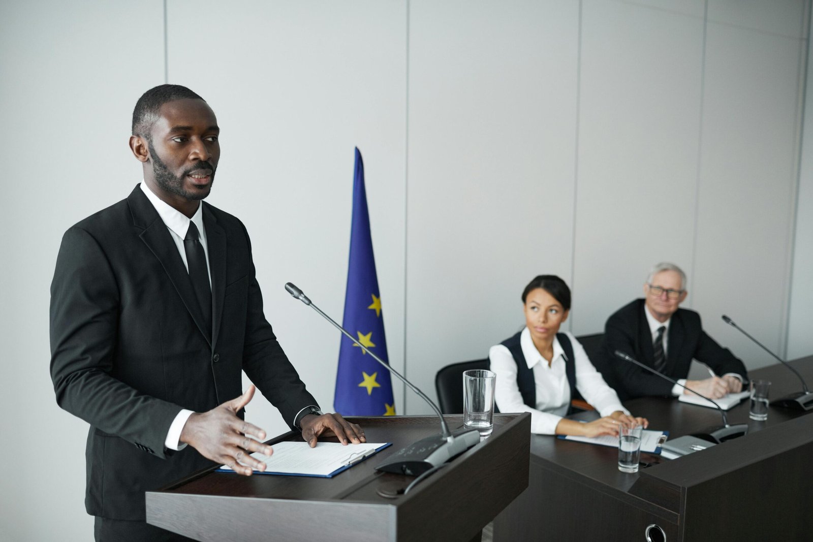 Business professional delivering speech in conference with colleagues listening attentively.