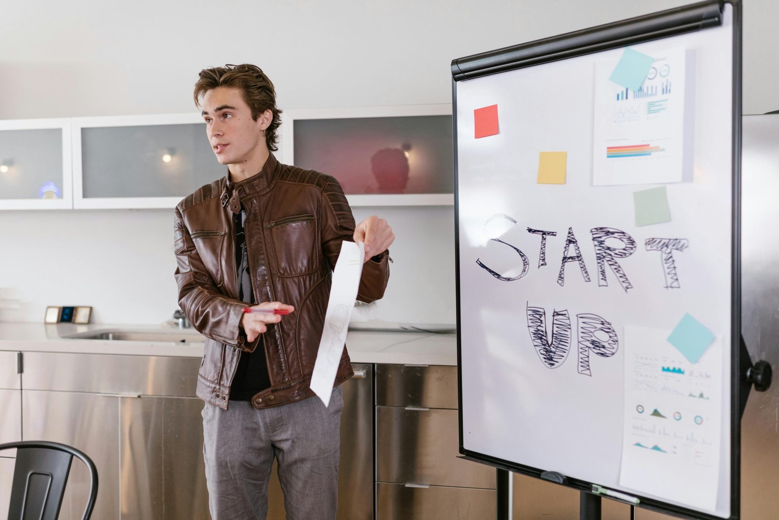 A young entrepreneur gives a presentation on startup strategies indoors with a flip chart.